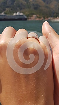 Girl s hand with a ring hepkily squeezes a guy s hand on the background of a cruise ship