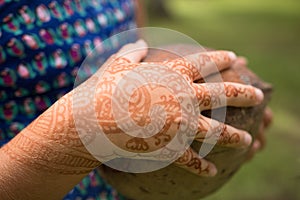 Girl's hand with temporary henna tattoo holds a coconut