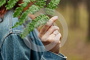 Girl's hand touching fern leaf. Macro. Forest theme, fashionable colors