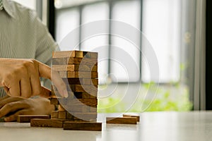 The girl`s hand tried to pull out the wooden block without tipping the tower. Physical skill group game with wooden blocks. Constr