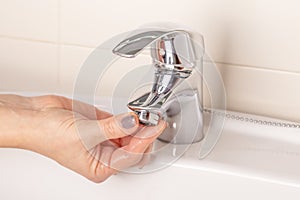 The girl`s hand twists off twists the faucet aerator in the bathroom photo