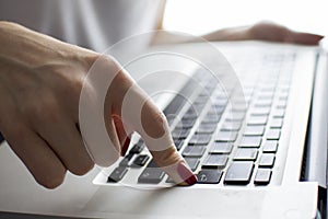 Girl`s hand typing on a laptop keyboard, she presses Enter key, moment of confirmation, close-up