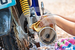 Girl's hand washing a motorcycle pipe to help family