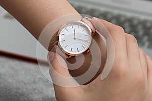 Girl`s hand with wrist watch in front of desk with laptop comput