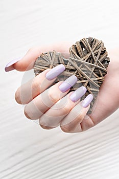 Girl`s hands with delicate purple manicure and decoratine heart