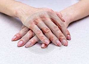 The girl`s hands with extended manicure lie on the bright table