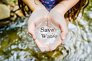 A girl's hands hold water with the words save water. Concept of saving water in the face of drought