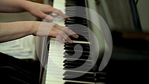 Girl`s hands on the keyboard of the piano. The girl plays piano,close up piano. Hands on the white keys of the Piano