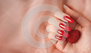 Girl`s hands with red manicure and decoratine heart