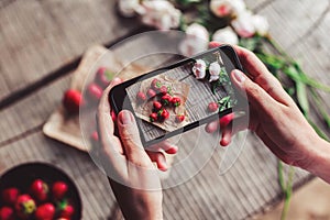 Girl`s hands taking photo of breakfast with strawberries by smartphone. Healthy breakfast, Clean eating
