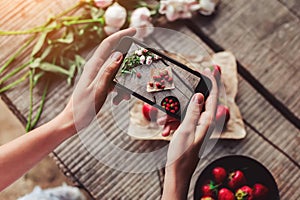 Girl`s hands taking photo of breakfast with strawberries by smartphone. Healthy breakfast, Clean eating, vegan food concept.
