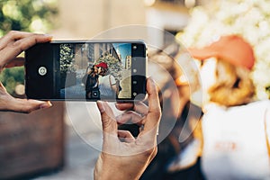 Girl`s hands taking photo of a couple of women kissing in a street of Madrid. Same sex relationship concept