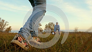 Girl`s leg hits soccer ball man catches ball. family plays football in park. dad and daughter play ball on the field.