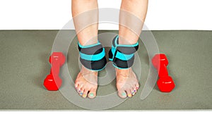 Girl's legs with ankle weights and dumbbells, isolated