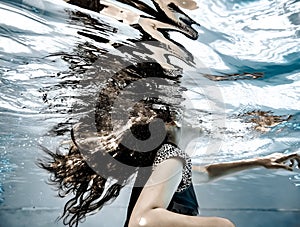 A girl`s long hair flowing underwater and reflections on the undersurface of the water