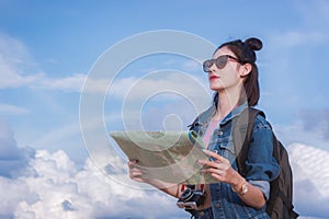 Girl`s looking at destination and hold a map on street