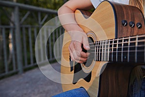 Girl`s plays the acoustic guitar outdoor.
