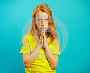 Girl with sad eyes asks to buy her something, folded hands in the palm of chest, expresses a request, has begging look.