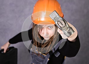 Girl in safety helmet orange vest holding hammer tool