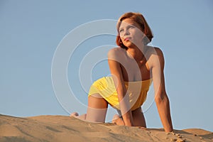 Girl in sand looks at a decline