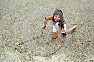 Girl in sand making hart photo