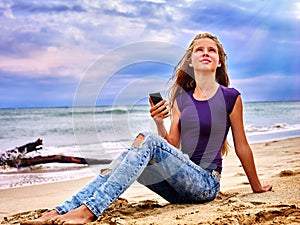 Girl on sand near sea call help by phone.