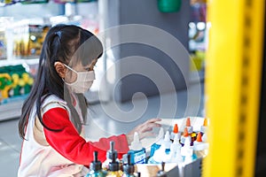 girl in sanitary face mask shopping at toy store. Child wearing protective mask against coronavirus