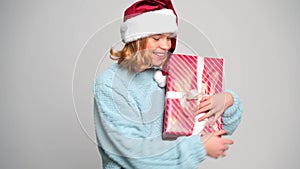 Girl in santa claus cap is given a red gift. Concept Christmas and New Year