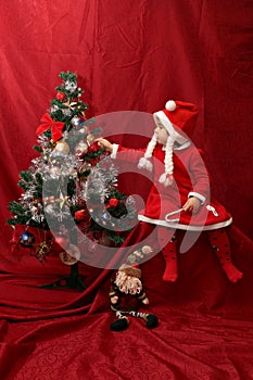 Girl with Santa Claus costume playing with a Christmas tree