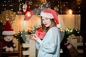 Girl in santa claus hat. Christmas shopping. Christmas tree. Winter holiday. Sexy woman with present box. Happy new year