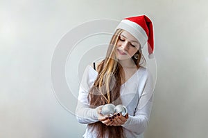 Girl in Santa hat with christmas balls in the hands