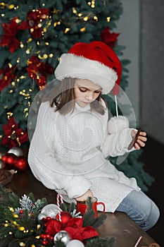 Girl in Santa hat for Christmas eats cookies and cocoa at home in kitchen