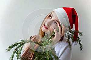 Girl in Santa hat with christmas green fir branches