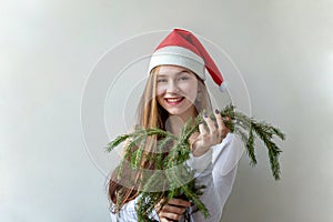 Girl in Santa hat with christmas green fir branches