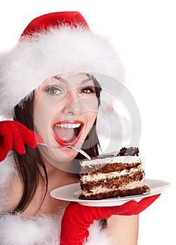 Girl in santa hat eat cake on plate.