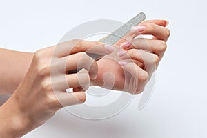 The girl saws with a nail file and shaped her nails during the nail extension procedure in a beauty salon. Professional hand care