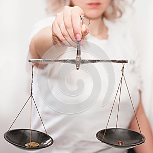 A girl with scales in her hands on a light background makes a decision, weighs the argument