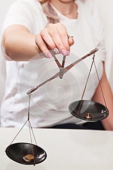 A girl with scales in her hands on a light background makes a decision, weighs the argument