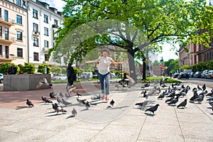 A girl scares a flock of pigeons in the city square