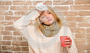 Girl in scarf hold tea mug and tissue. Runny nose and other symptoms of cold. Cold and flu remedies. Remedies should