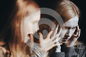 Girl with schizophrenia covering ears photo