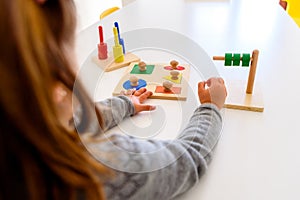 Girl in a school developing her motor skills in the hands using a colored wood material