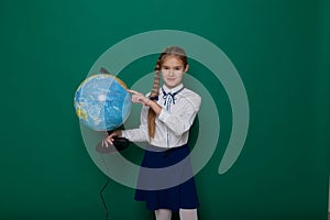 Girl school girl is standing at the Blackboard with globe