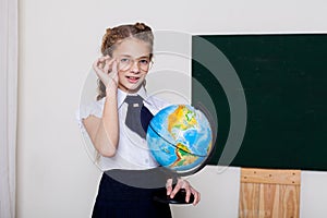 Girl school girl is standing at the Blackboard with globe