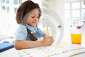 Girl In School Uniform Doing Homework In Kitchen