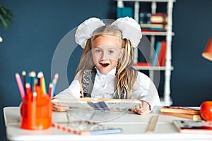 A girl in a school uniform looks at a textbook with a surprised face. girl trying to study having too many homework that It`s