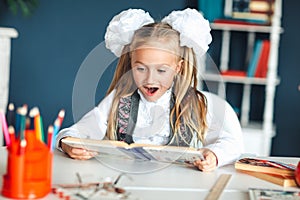 A girl in a school uniform looks at a textbook with a surprised face. girl trying to study having too many homework that It`s