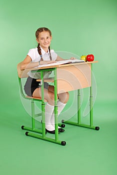 Girl in a school uniform sitting at a desk and reading a book
