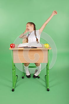 Girl in a school uniform sitting at a desk and yawns