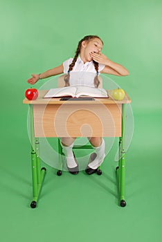 Girl in a school uniform sitting at a desk and yawns